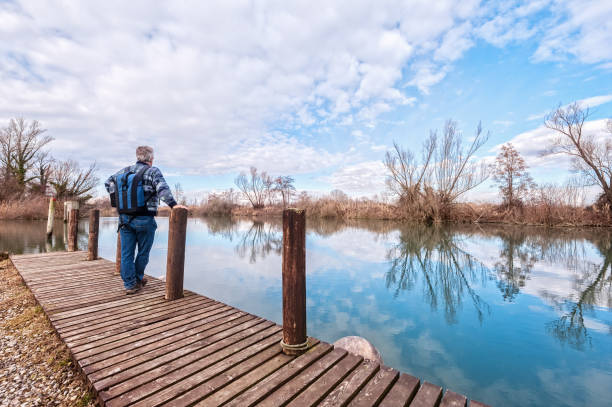 istock Hiker with backpack over wood pier on shore of river. 1050254500