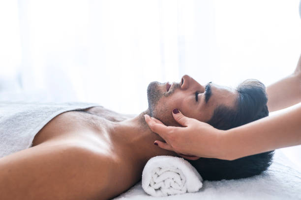 スパでのトリートメントを得る若い男性のクローズ アップ - facial massage ストックフォトと画像