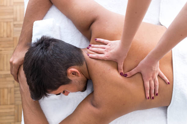 молодой человек наслаждается массажем на спа-процедуре - massage therapist massaging sport spa treatment стоковые фото и изображения