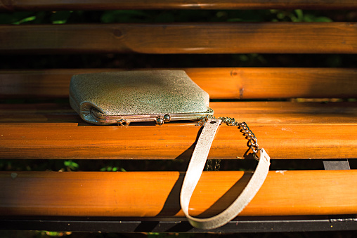 Beautiful bag for women, lying on a wooden bench. A warm summer evening
