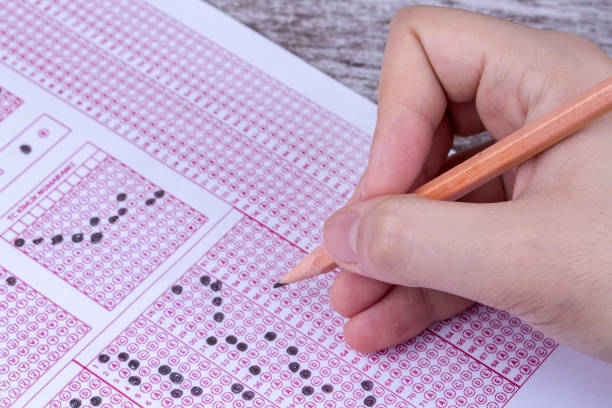 istock Students hand doing exams quiz test paper with pencil drawing selected choice on answer sheets at school 1050263936