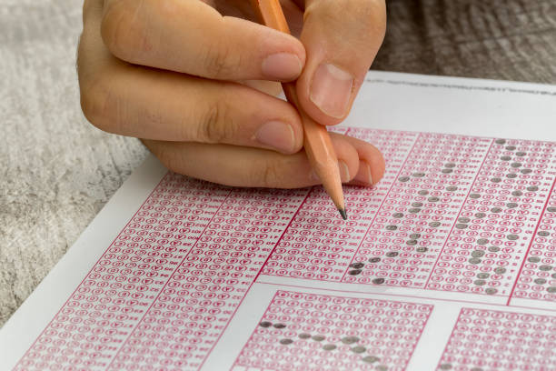 istock Students hand doing exams quiz test paper with pencil drawing selected choice on answer sheets at school 1050263968