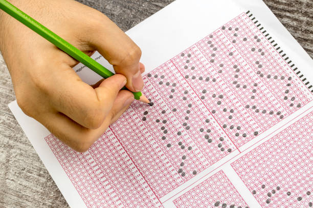 istock Students hand doing exams quiz test paper with pencil drawing selected choice on answer sheets at school 1050264016