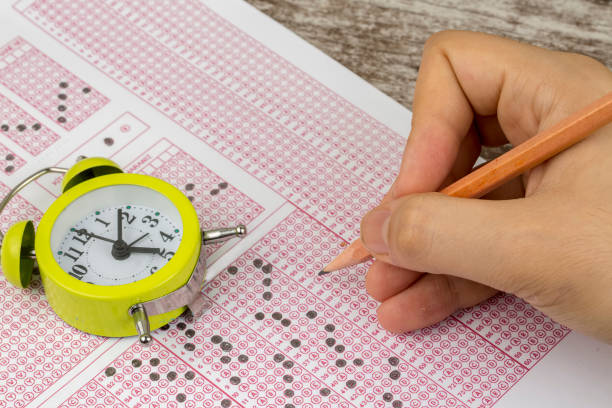 istock Students hand doing exams quiz test paper with pencil drawing selected choice on answer sheets at school 1050264018