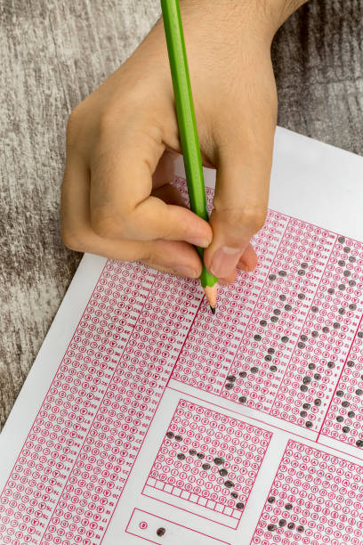 istock Students hand doing exams quiz test paper with pencil drawing selected choice on answer sheets at school 1050264022