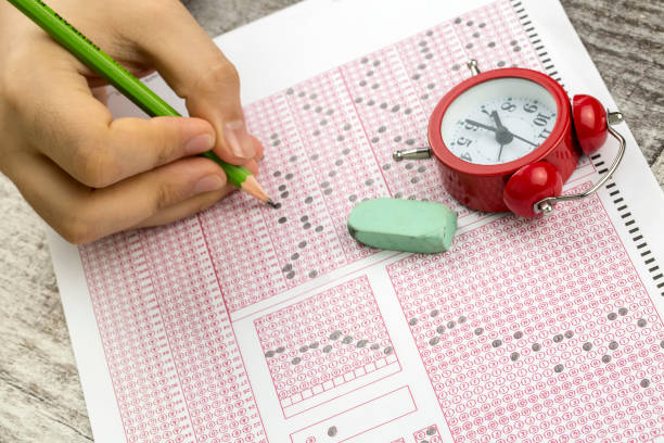 istock Students hand doing exams quiz test paper with pencil drawing selected choice on answer sheets at school 1050264040