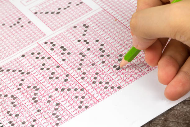 istock Students hand doing exams quiz test paper with pencil drawing selected choice on answer sheets at school 1050264070