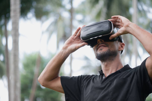istock Man in virtual reality headset playing video game outdoors 1050274376