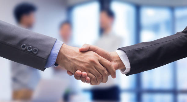 close up two businessman hand shake together for agreement successful on blur group of businesspeople talking in meeting room , achievement concept