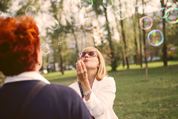 istock Senior woman blowing soap bubbles in park 1050284448