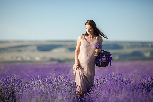 Cute smiling pregnant woman resting in a lavender field. Posing outdoors. Motherhood. Motherhood.Lavender field and a happy pregnant woman.Young beautiful pregnant woman on summer meadow in grass on bright Sunny day.
