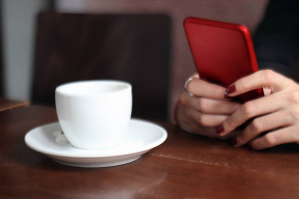 istock Cafe cup with woman hands on mobile phone 1050287316