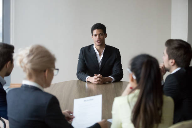 istock Group of employees interviewing new african worker at office boardroom 1050287460