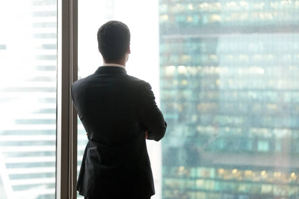 istock Successful thoughtful businessman looking through the window at skyscrapers 1050287540