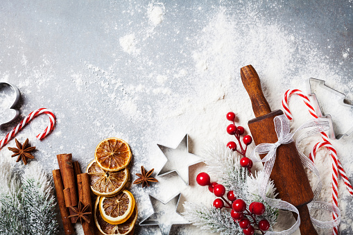 Bakery food background for cooking christmas baking with rolling pin, scattered flour and spices decorated with fir tree top view.