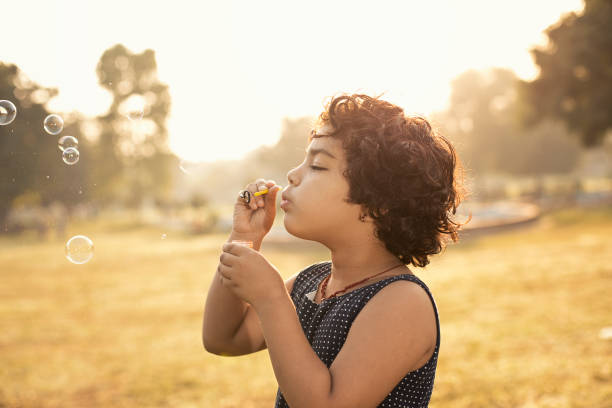 Little Indian girl blowing bubbles at public park