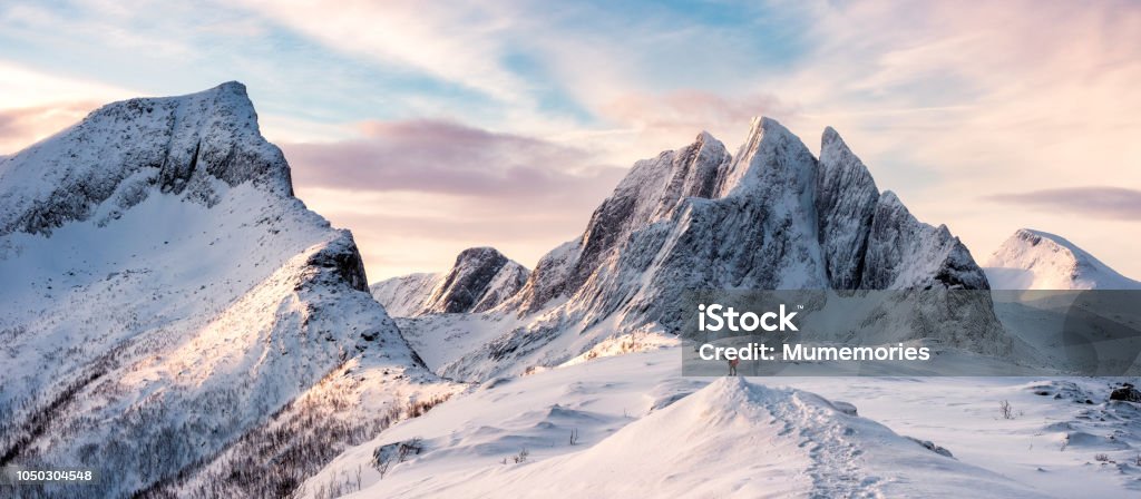 Panorama of Mountaineer standing on top of snowy mountain range Panorama of Mountaineer standing on top of snowy mountain range at Senja, Norway Mountain Stock Photo