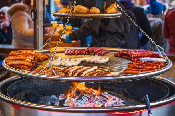 grilling sausages on barbecue grill at christmas market winter wonderland, london - broiling imagens e fotografias de stock