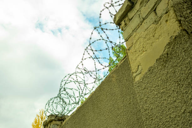 istock brick wall with barbed wire against the sky 1050308502