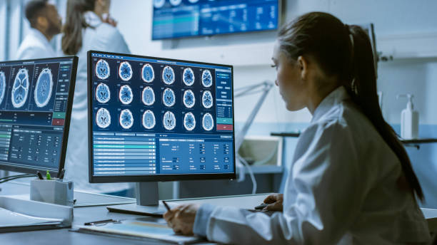 Female Medical Research Scientist Working with Brain Scans on Her Personal Computer, Writing Down Data in a Clipboard. Modern Laboratory Working on Neurophysiology, Science, Neuropharmacology. Female Medical Research Scientist Working with Brain Scans on Her Personal Computer, Writing Down Data in a Clipboard. Modern Laboratory Working on Neurophysiology, Science, Neuropharmacology. technology office equipment laboratory stock pictures, royalty-free photos & images