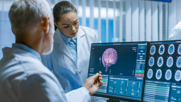 istock Two Medical Scientists in the Brain Research Laboratory Discussing Progress on the Neurophysiology Project Fighting Tumors. Neuroscientists Use Personal Computer with MRI, CT Scans Show Brain Images. 1050311556