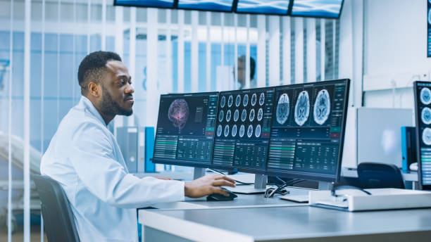 istock Medical Scientist Working with CT Brain Scan Images on a Personal Computer in Laboratory. Neurologists in Neurological Research Center Working on a Brain Tumor Cure. 1050311706