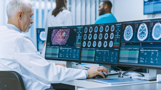 istock Experienced Senior Scientist Working with CT/ MRI Brain Scan Images on a Personal Computer in Laboratory. Neurologists / Neuroscientists in Medical Research Center Work on Brain Tumor Cure. 1050311774