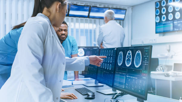 istock Diverse Team of Medical Scientists Solve Problems and Point at Computer Screens Showing CT, MRI Scans. Neurologists / Neuroscientists Working in Brain Research Laboratory. 1050311784