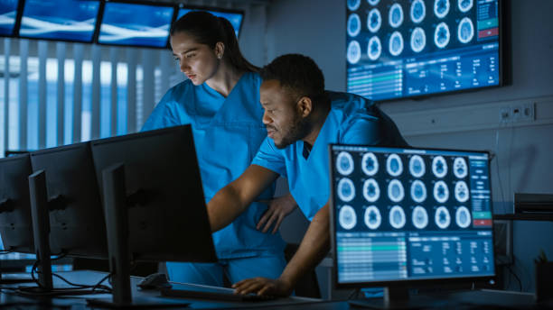 istock Two Medical Scientists / Neurologists, Talking and Working on a Personal Computer in Modern Laboratory. Research Scientists Making New Discoveries in the fields of Neurophysiology, Science, Neuropharmacology. Understanding Human Brain. 1050312892