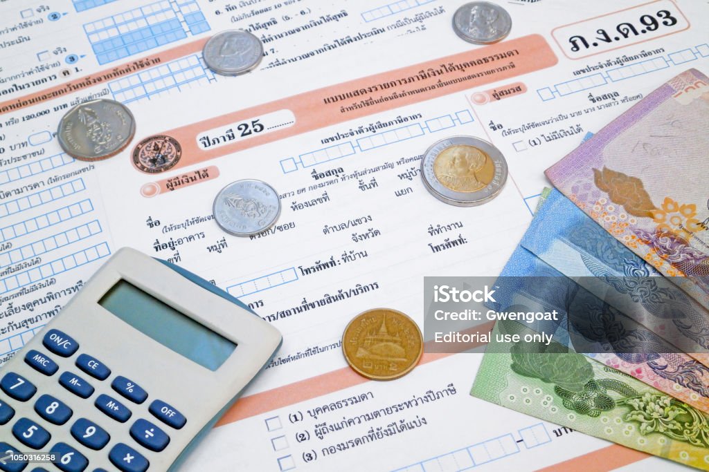 Thai income tax form Bangkok, Thailand - October 05 2018: A calculator and some baht coins and banknotes on the top of a Thai income tax form (ภ.ง.ด.93). Tax Stock Photo Thai income tax form Bangkok, Thailand - October 05 2018: A calculator and some baht coins and banknotes on the top of a Thai income tax form (ภ.ง.ด.93). Tax Stock Photo