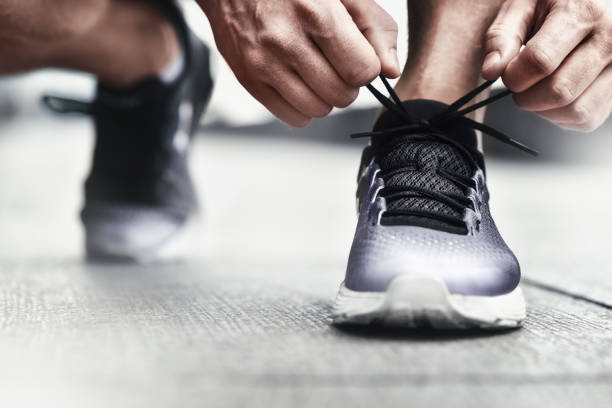 gros plan sportif attachant des espadrilles. homme méconnaissable s’arrêtant le laçage des chaussures à l’extérieur. concept de chaussures de sport. version couleur - ni hao photos et images de collection