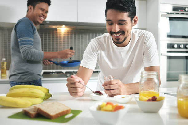 coppia omosessuale che cucina la colazione in cucina - alternative health care foto e immagini stock