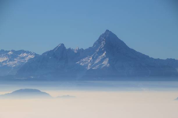 vista de la montaña watzmann, alemania, en invierno. una capa de neblina alta sobre el valle de salzburgo. austria, alemania. - mythology snow winter austria fotografías e imágenes de stock