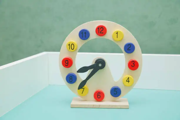 Colorful wooden toy clock in textured foam for kid to learn about the time . beautiful wooden colorful clock dial clock-face on isolated white background . Creative clock face design modern colorful.