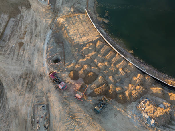 istock Aerial view of three multi-colored dump tip trucks unloading in a designated place at a construction site, soil poured out from a quarry poured out of a quarry, around a large number of sand mounds 1050350022