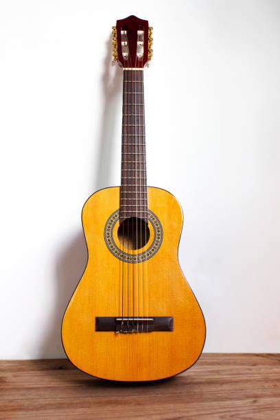 istock Classic guitar on wood floor with white wall. 1050365398