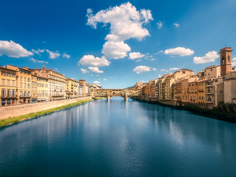 Panoramic view of Ponte Vecchio Bridge Florence with dramatic cloudy sky and reflection on river, Italy. Clipping path of sky