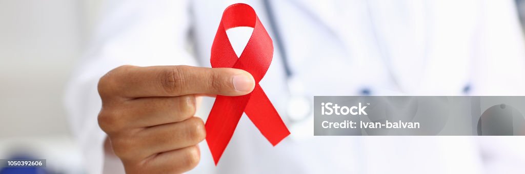 Black woman doctor holding a red ribbon Black woman doctor holding a red ribbon in his hand an international day of protecting people from cancer by symbol of struggle and survival mankind AIDS Stock Photo