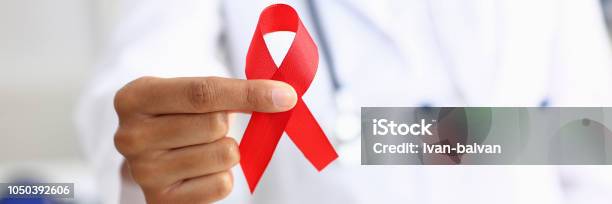 Black Woman Doctor Holding A Red Ribbon Stock Photo - Download Image Now - AIDS, Ribbon - Sewing Item, Medical Exam