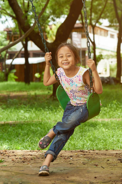 istock Asian girl on a swing playing at a park 1050392888
