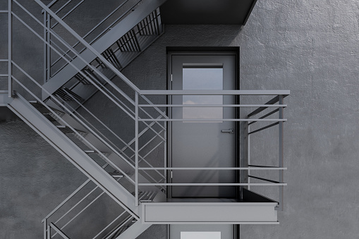 Closed door of an emergency fire exit in a concrete building wall with gray staircase. 3d rendering mock up