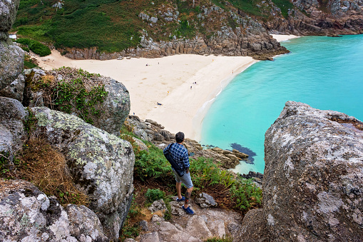 Man looking  over Porthcurno Beach, Pedn Vounder beach and Logan Rock  seen from Minack Open Air Theatre; Cornwall; England; UK