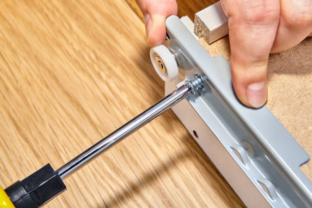 istock Installation furniture, screwing screw-bolt with using hand screwdriver, close-up. 1050416314