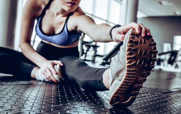 image de femme fitness jeune magnifique assis dans la salle de gym près de fenêtre tandis que faire des exercices d’étirement. - stretching photos et images de collection