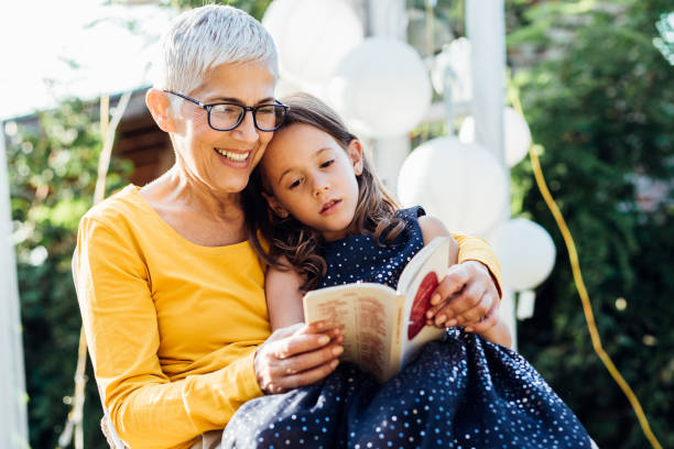 senior woman reading to granddaughter - grandparent reading grandmother child imagens e fotografias de stock