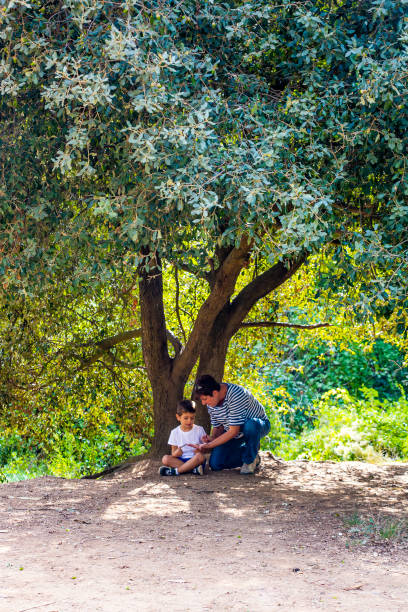 istock Little boy and his grandma seated  under a huge tree 1050423610