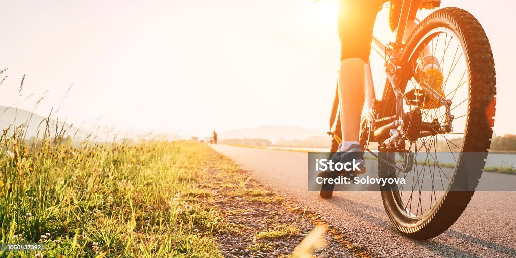 Pies de mujer en bycikle el pedal de la luz del atardecer - Foto de stock de Andar en bicicleta libre de derechos