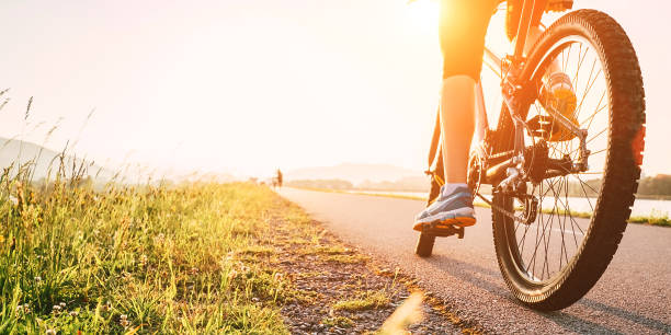 piedi donna su pedale bycikle alla luce del tramonto - chain bicycle chain gear equipment foto e immagini stock