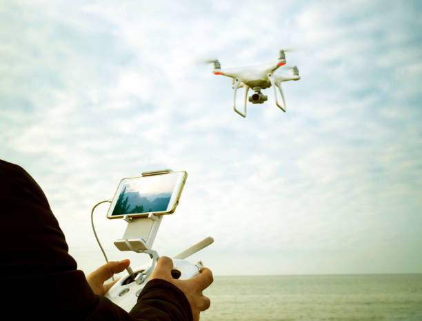 quadrocopter drone take 4k video to landscape with remote control unit at man hands stock photo