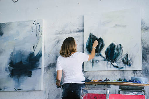 Artist mid-adult woman working in art studio, abstract oil paint on canvas.